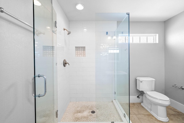 bathroom with tile patterned floors, a shower with shower door, and toilet