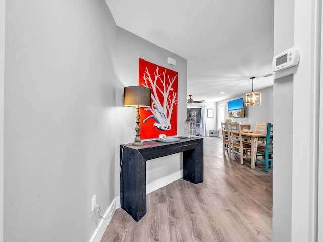 hallway with hardwood / wood-style floors and an inviting chandelier