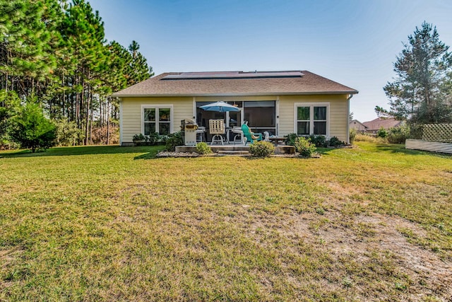 back of house with solar panels and a yard