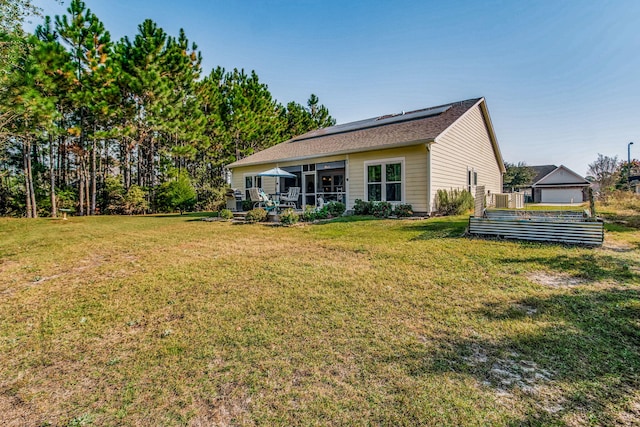 back of house featuring a lawn, solar panels, and a garage