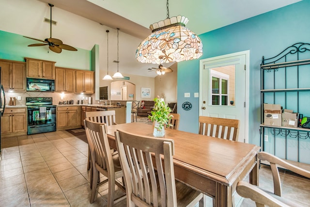 tiled dining space featuring ceiling fan, sink, and a high ceiling