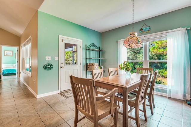 dining space with light tile patterned floors and vaulted ceiling