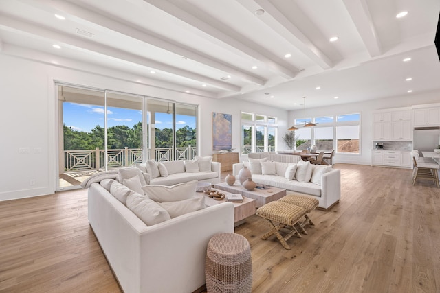 living room with beamed ceiling, plenty of natural light, and light wood-type flooring