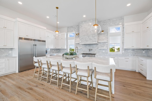 kitchen featuring white cabinets, plenty of natural light, stainless steel built in fridge, and light wood-type flooring