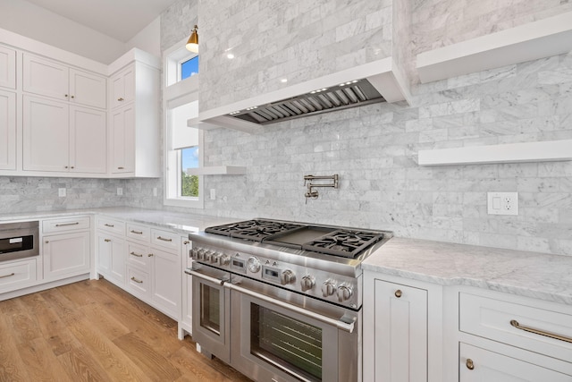 kitchen featuring white cabinetry, light stone counters, light hardwood / wood-style floors, decorative backsplash, and appliances with stainless steel finishes