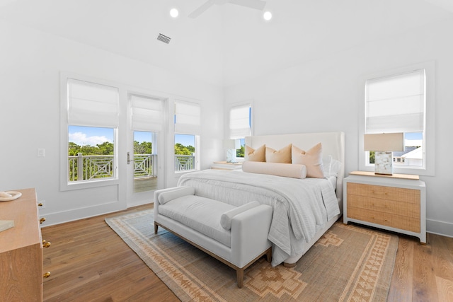 bedroom with ceiling fan, access to exterior, wood-type flooring, and multiple windows