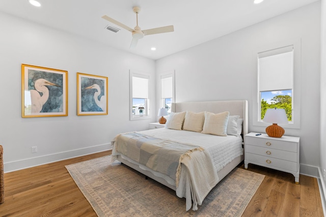 bedroom with dark hardwood / wood-style floors, ceiling fan, and multiple windows