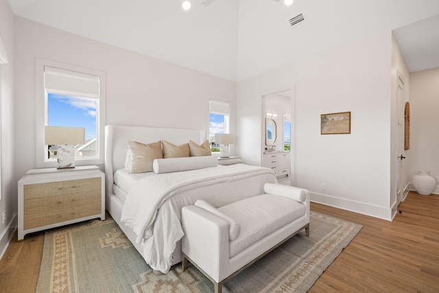 bedroom featuring wood-type flooring, ensuite bath, and multiple windows