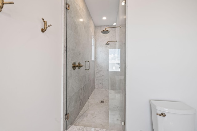 bathroom featuring toilet and a shower with door