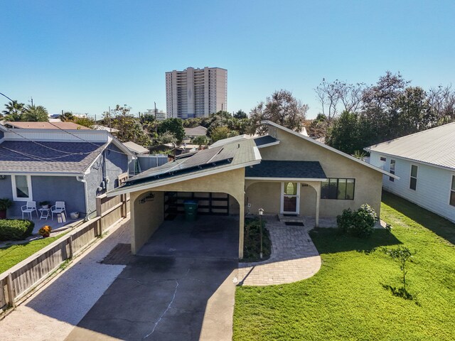 view of front of house with a front yard, solar panels, and a carport