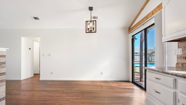 unfurnished dining area with dark hardwood / wood-style floors, an inviting chandelier, and vaulted ceiling