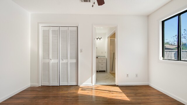 unfurnished bedroom with a closet, ceiling fan, and dark hardwood / wood-style flooring