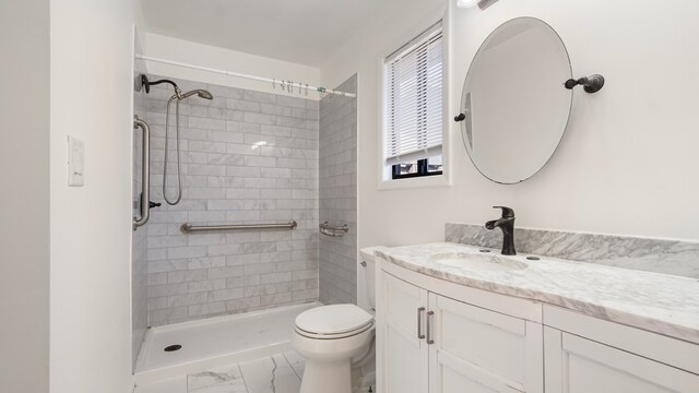 bathroom featuring vanity, toilet, and a tile shower