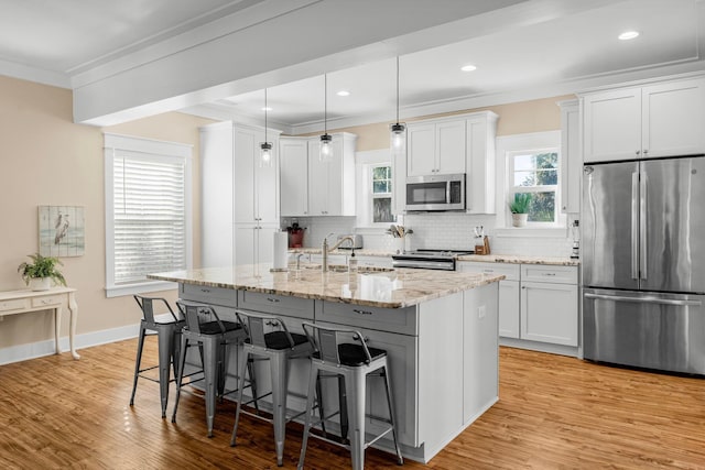 kitchen featuring sink, light hardwood / wood-style flooring, an island with sink, white cabinets, and appliances with stainless steel finishes