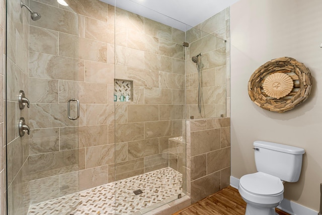 bathroom with wood-type flooring, a shower with shower door, and toilet