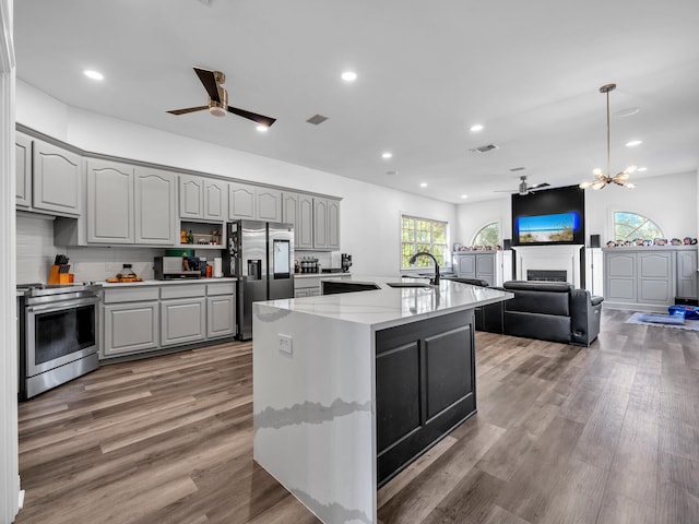 kitchen featuring appliances with stainless steel finishes, sink, hardwood / wood-style floors, gray cabinets, and an island with sink