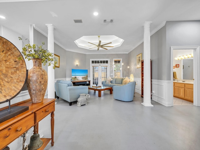 living room with decorative columns, ceiling fan, ornamental molding, and a tray ceiling