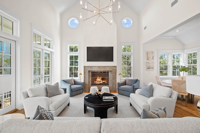 living room featuring high vaulted ceiling, a notable chandelier, and light wood-type flooring