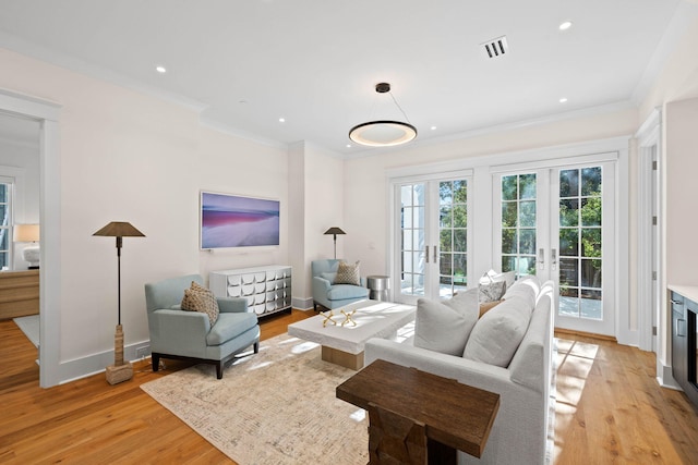 living room featuring french doors, light hardwood / wood-style floors, and ornamental molding