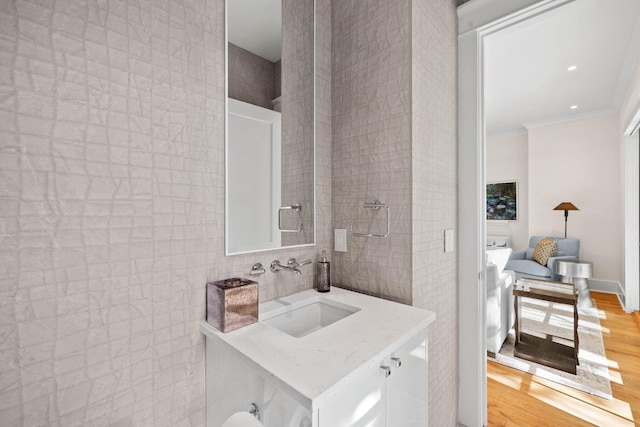 bathroom with crown molding, vanity, wood-type flooring, and tile walls