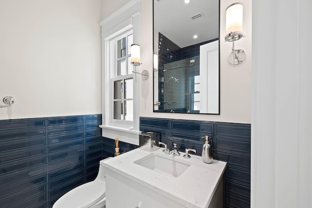 bathroom with plenty of natural light, toilet, tile walls, and vanity