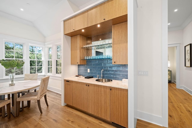 interior space with light wood-type flooring, vaulted ceiling, crown molding, and sink