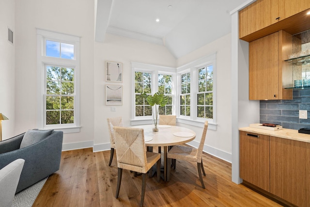 dining space featuring a wealth of natural light, light hardwood / wood-style flooring, and vaulted ceiling