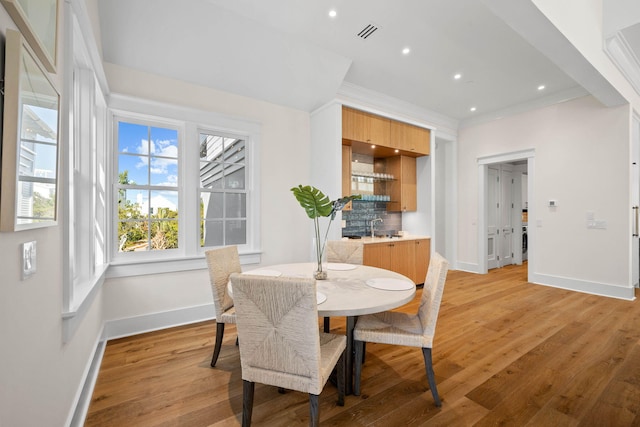 dining area featuring hardwood / wood-style flooring, crown molding, and sink