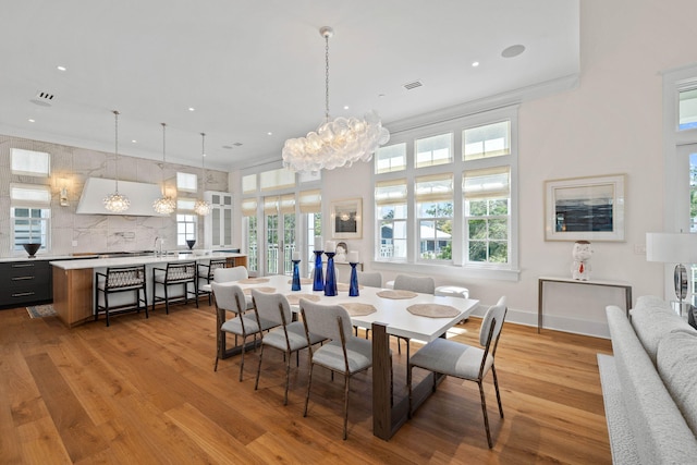 dining area with a chandelier, light hardwood / wood-style flooring, ornamental molding, and sink