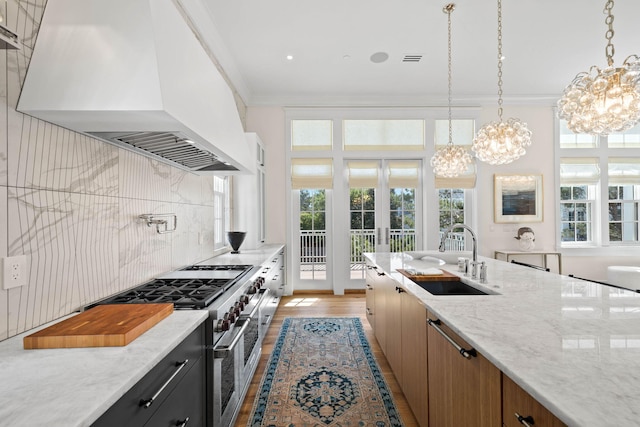 kitchen featuring custom exhaust hood, crown molding, sink, range with two ovens, and light hardwood / wood-style flooring