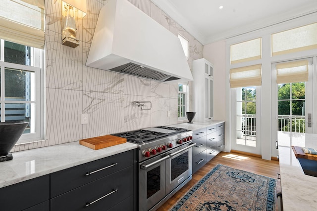 kitchen featuring custom exhaust hood, double oven range, dark wood-type flooring, crown molding, and light stone counters