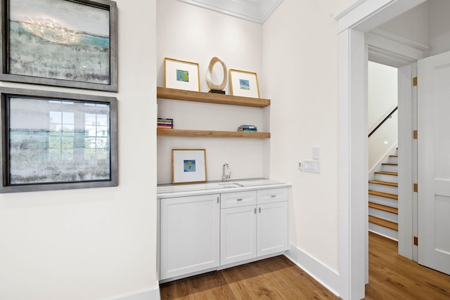 corridor featuring sink, light wood-type flooring, and crown molding