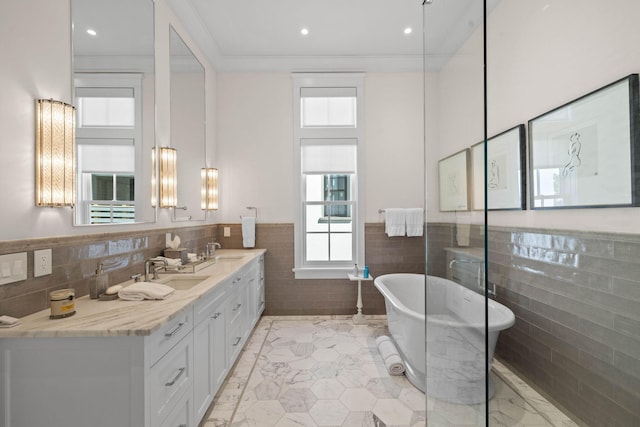 bathroom featuring vanity, a bath, and tile walls