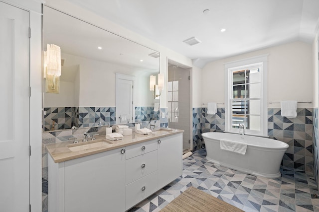 bathroom with a wealth of natural light, vanity, tile walls, and a bathing tub