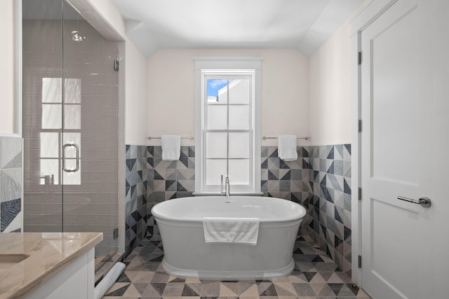 bathroom with tile patterned flooring, separate shower and tub, vaulted ceiling, and tile walls