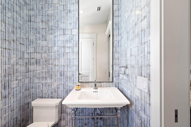 bathroom featuring toilet and tile walls