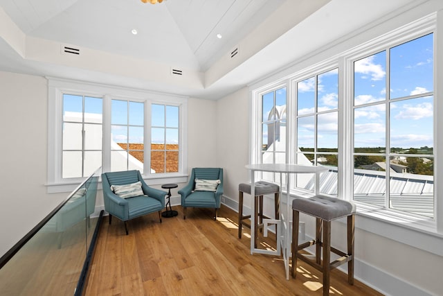 sitting room with a tray ceiling and light wood-type flooring