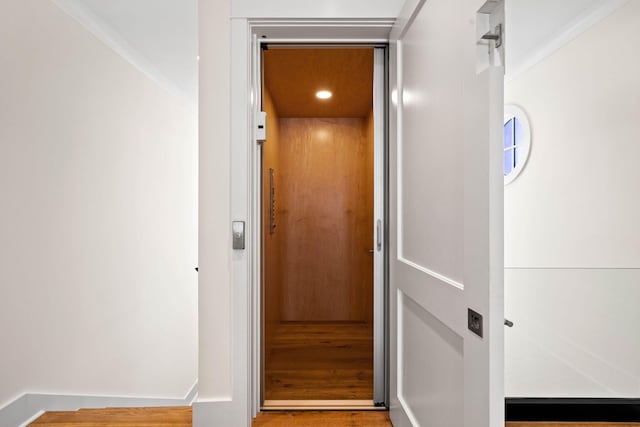 interior details with elevator and hardwood / wood-style flooring