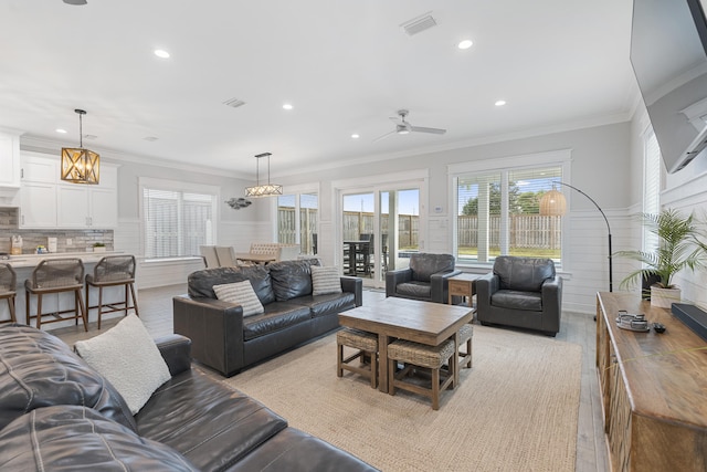 living room with ceiling fan, ornamental molding, and light wood-type flooring