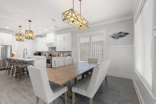 dining room with hardwood / wood-style flooring, ornamental molding, and sink