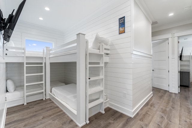 bedroom featuring wooden walls, hardwood / wood-style floors, and ornamental molding