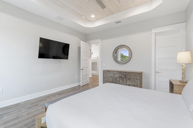 bedroom featuring wood-type flooring, a tray ceiling, and wooden ceiling