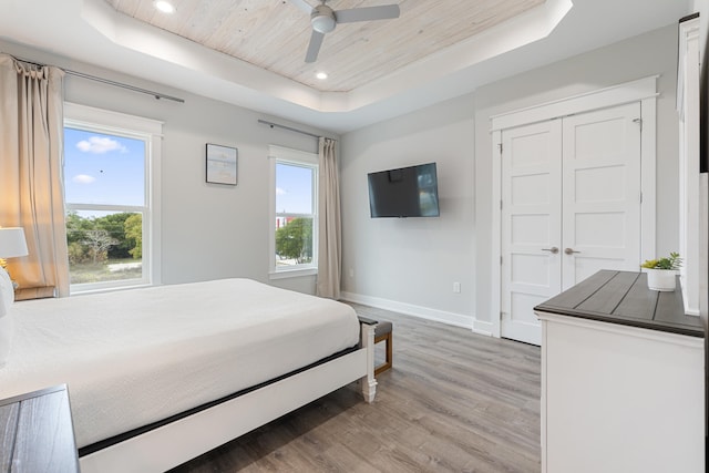 bedroom with a raised ceiling, ceiling fan, wood-type flooring, wood ceiling, and a closet