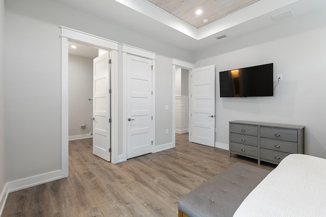 bedroom featuring a tray ceiling, wood ceiling, and light wood-type flooring