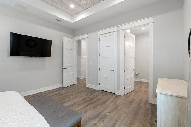 bedroom with a raised ceiling and wood-type flooring