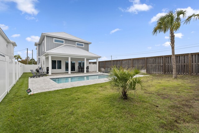 rear view of property with a fenced in pool, a yard, and a patio