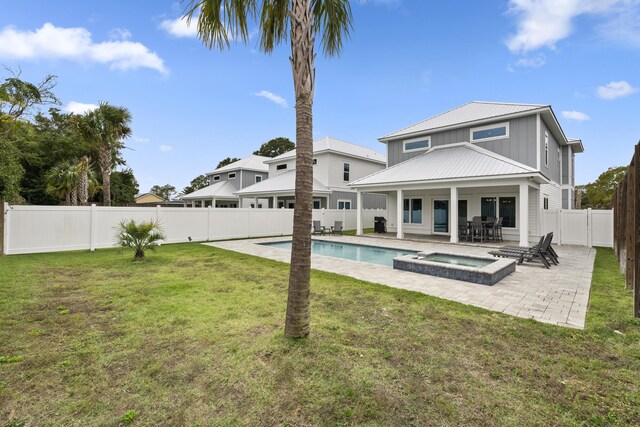 back of property featuring a swimming pool with hot tub, a yard, and a patio