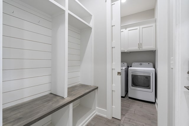 laundry room with cabinets, washing machine and dryer, and light hardwood / wood-style flooring