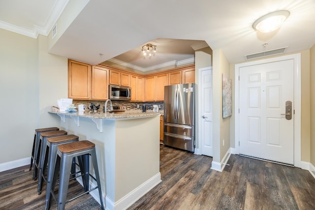 kitchen with kitchen peninsula, tasteful backsplash, light stone counters, stainless steel appliances, and dark hardwood / wood-style floors