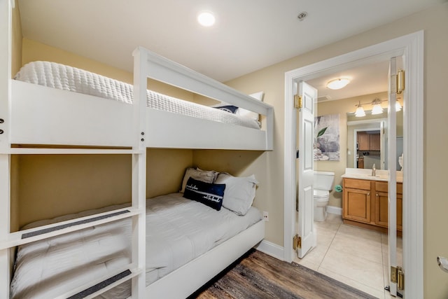 bedroom with hardwood / wood-style floors, ensuite bathroom, and sink